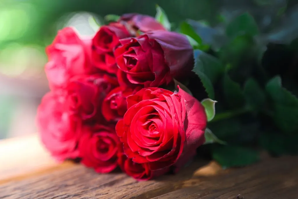 A bouquet of red and pink roses on a wooden table