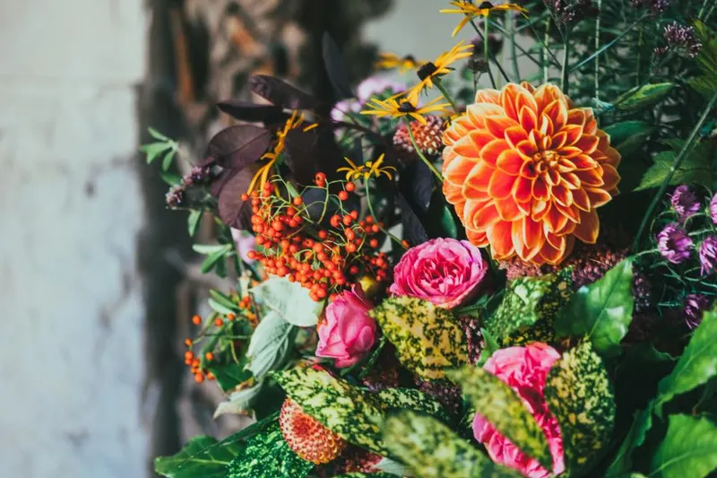 A colorful mixed bouquet with an orange dahlia and pink roses